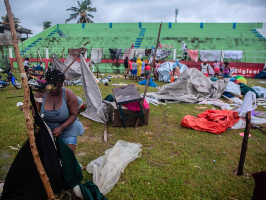 In the aftermath of Tropical Storm Grace, a woman works on a shelter at an improvised camp at Parc Lande de Gabion stadium.