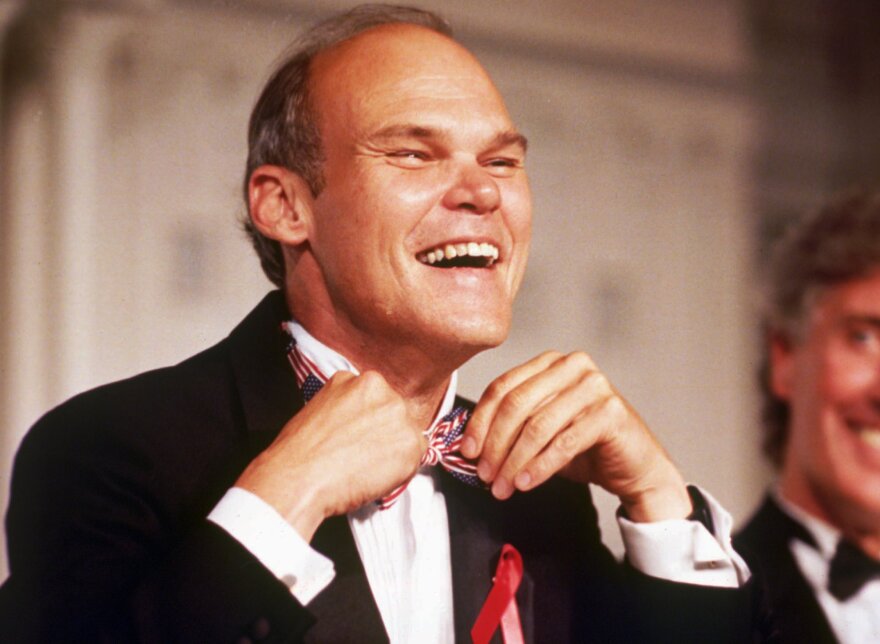 a man adjusts his bow tie while smiling