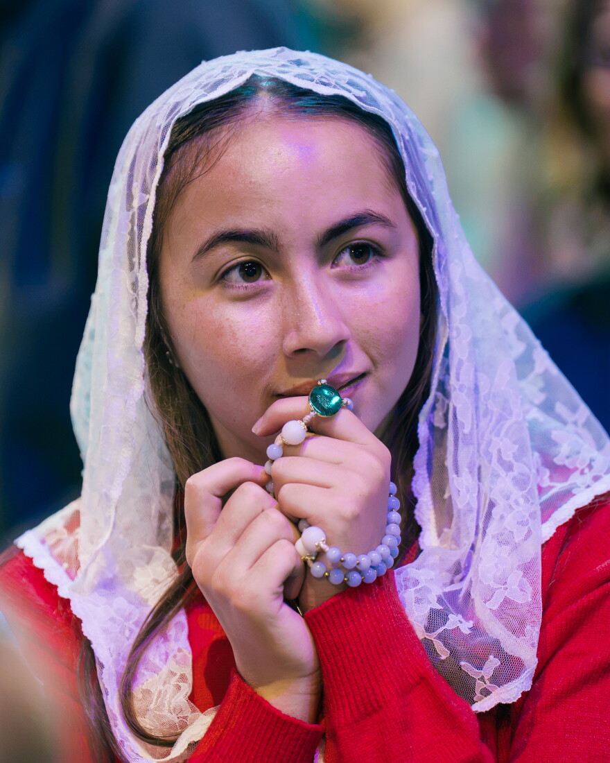 A woman wearing a white lace mantilla prays with a rosary during the beatification Mass for the late Archbishop Fulton J. Sheen on Thursday.