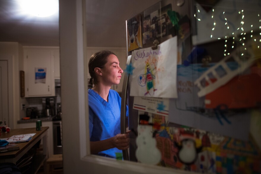 Dr. Heather Rybasack-Smith puts away eggs she has collected from her chickens and gets a drink from her fridge after working a 3-11 p.m. shift on Tuesday at the new field hospital at the convention center in Providence, R.I.