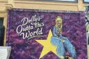a mural of country singer Dolly Parton sitting on a yellow star with the words "Dolly's Outta This World."