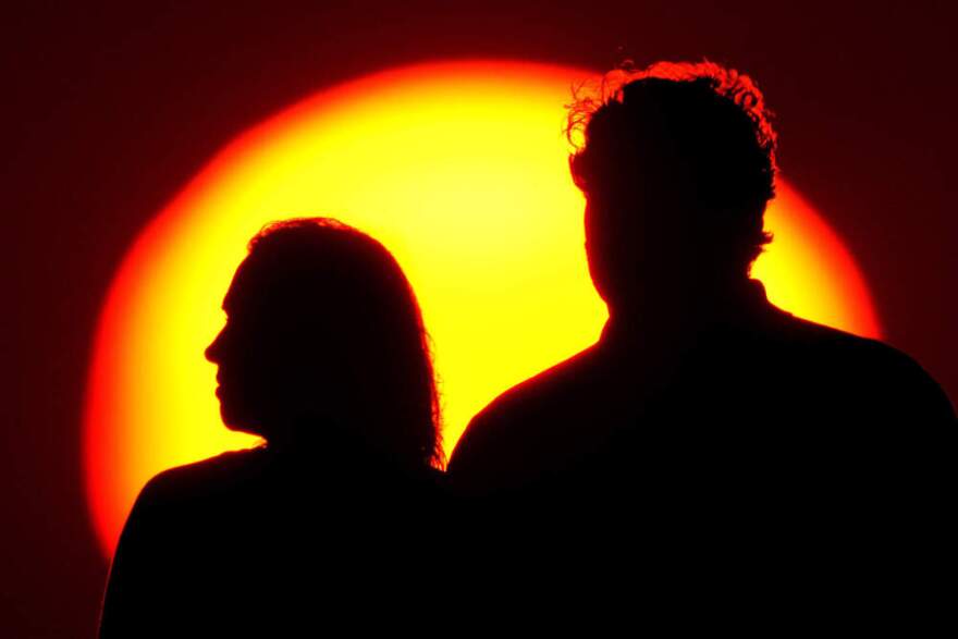 Family members watch the sun set from a park. (Charlie Riedel/AP)