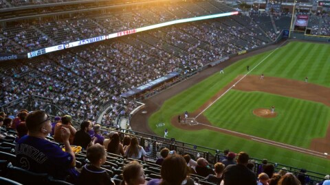 A family of four watches a Rockies baseball game at Coors Field, Aug. 15, 2023, in Denver.