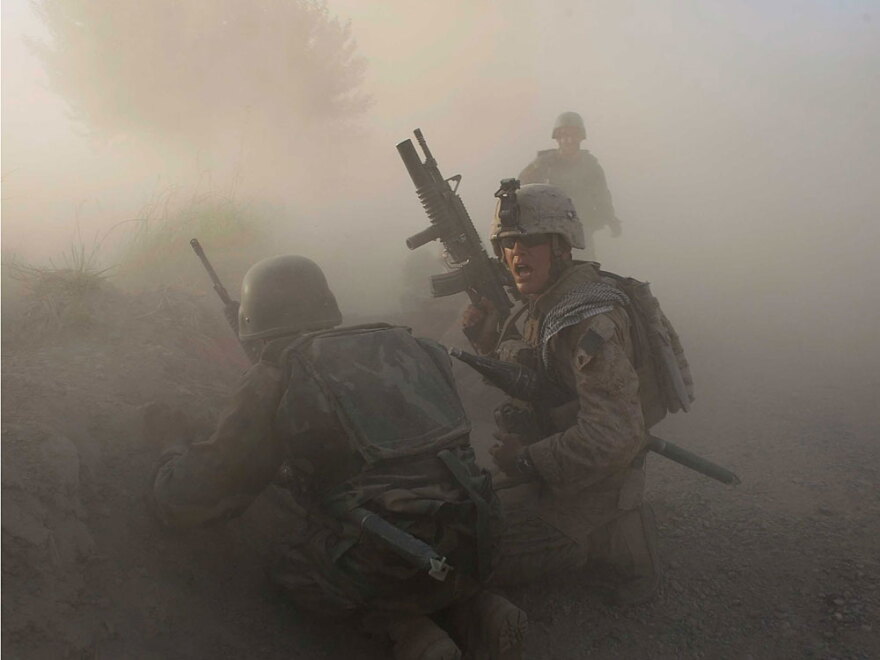 A U.S. Marine and an Afghan soldier react as dust blankets the area after an improvised explosive device exploded while they were under enemy fire on July 17 in Mian Poshteh, Afghanistan.