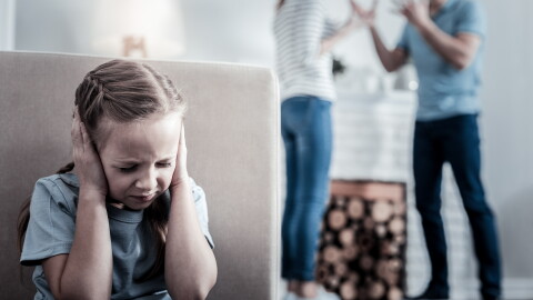 Too much stress. Little nervous girl closing her ears while hearing quarrels