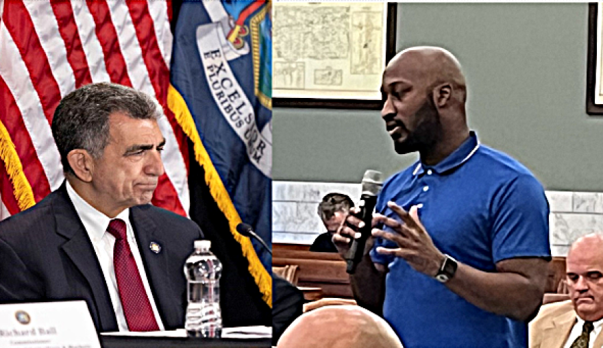 New York State Assembly member Bill Magnarelli seated at a microphone and Onondaga County Legislator Maurice Brown standing in a meeting with a microphone