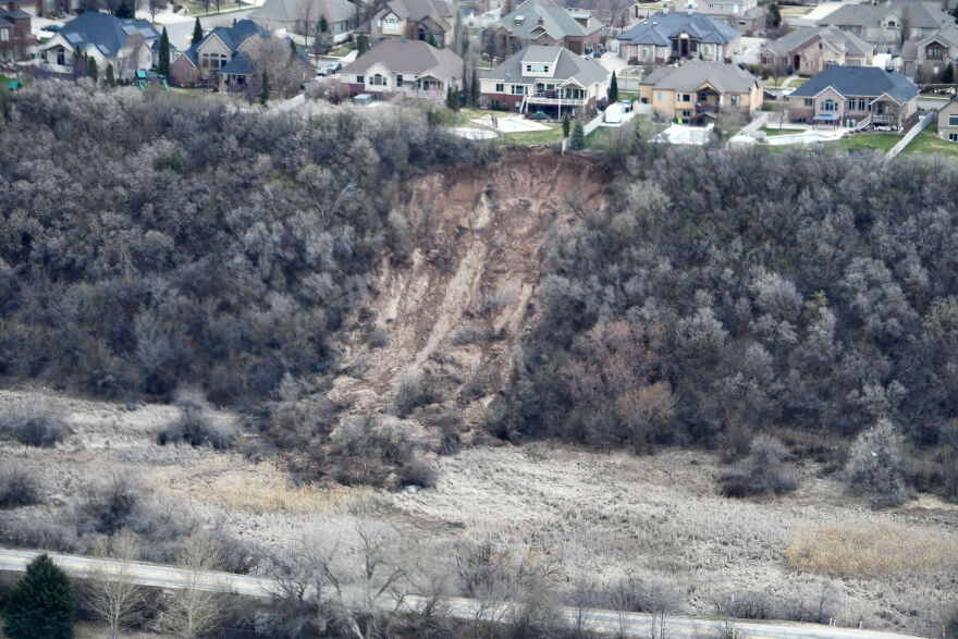  A row of homes in Layton sit atop a bluff, while a section of dirt is exposed below due to a landslide.