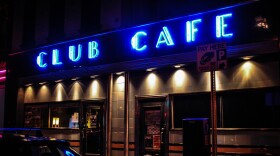 The exterior of a nightclub with a neon sign reading "Club Cafe."