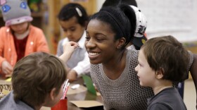 In this photo taken Friday, Feb. 12, 2016, assistant teacher D'onna Hartman smiles as she works with children at the Creative Kids Learning Center, a school that focuses on pre-kindergarten for 4- and 5-year-olds, in Seattle.