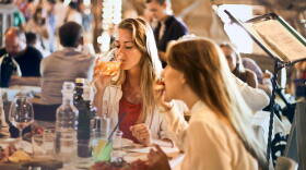 Two friends eat dinner in a crowded restaurant