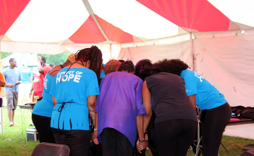 Hair stylists from Elaine Steven Beauty College pray in a circle before starting the free haircuts offered at the Convoy of Hope outreach Fair in Ferguson Saturday, July 25, 2015.