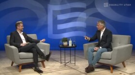 Photo of two men sitting in grey armchairs.