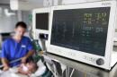 A male nurse sits at a patient's bed at the intensive care unit in the  hospital. (Jens Meyer/AP)