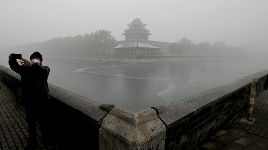 A tourist takes a selfie near the Turret of the Forbidden City in Beijing. The city issued a "red alert" Monday over dangerous levels of air pollution.