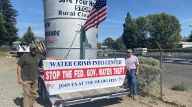  Grant Knoll, left, and Dan Nielsen, right, pose for a photo on Monday
with the bucket used in a demonstration in 2001, now parked next to
the "A" Canal headgates in Klamath Falls.