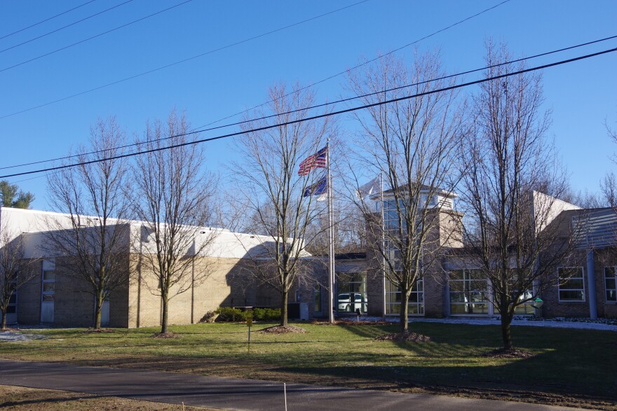 beige building with glass windows and flags in front , green grass