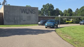 An image of the WLNS station with a circle driveway and a few cars parked.