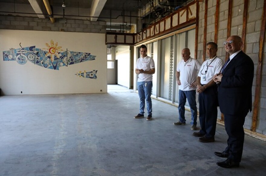 Delta-X employees from left, Mark Douglas, rehab project manager; Joe Shufelt, facilities manager; John Picardo, facilities engineer, and Derek Dlugosh-Ostap, the company's CEO, stand before the mural uncovered in the former Kodak building they are rehabbing.