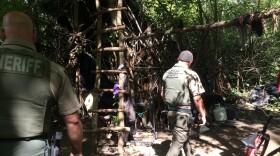 Jackson County Sheriff's deputies walk through a years-old encampment hidden near the Bear Creek Greenway outside Medford, an elaborate set of structures that deputies call "the Hobbit House."