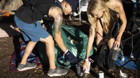 Two people pick up cans at a music festival. 