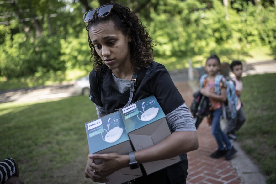 Catherine Manson unloads home nebulizer units from her car while her children, Caydence Manson, center, and Carter Manson, follow behind after they were picked up from school in Hartford, Conn., on Wednesday, May 25, 2022. All three of them suffer from asthma. The children have missed weeks of school, leaving them behind in schoolwork at a critical juncture for their education. And in turn, their parents were forced to miss work to care for them – putting a strain on the family’s finances.
