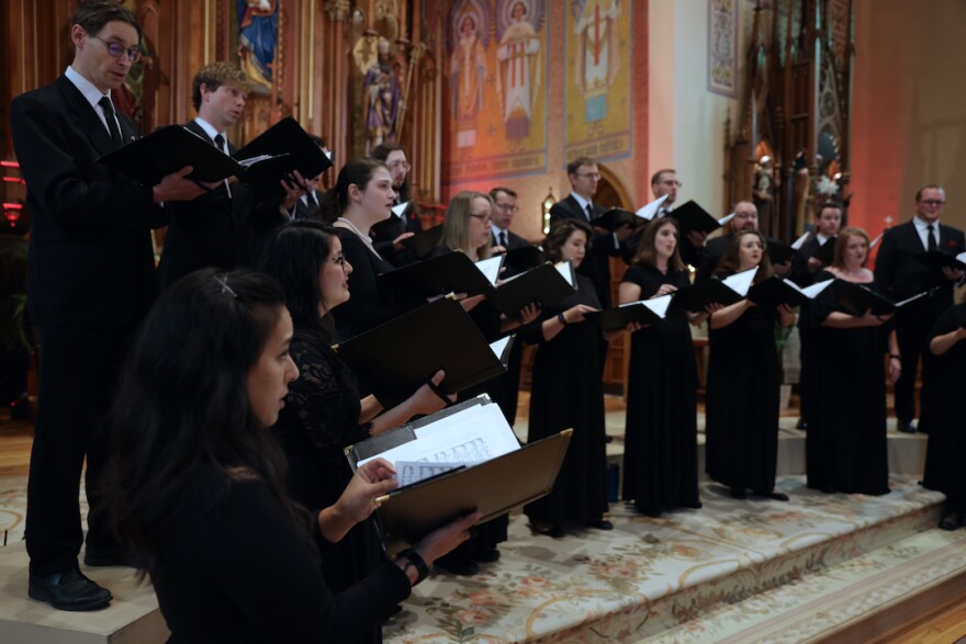 choir of men and women dressed in black and standing in a semi-circle in a church