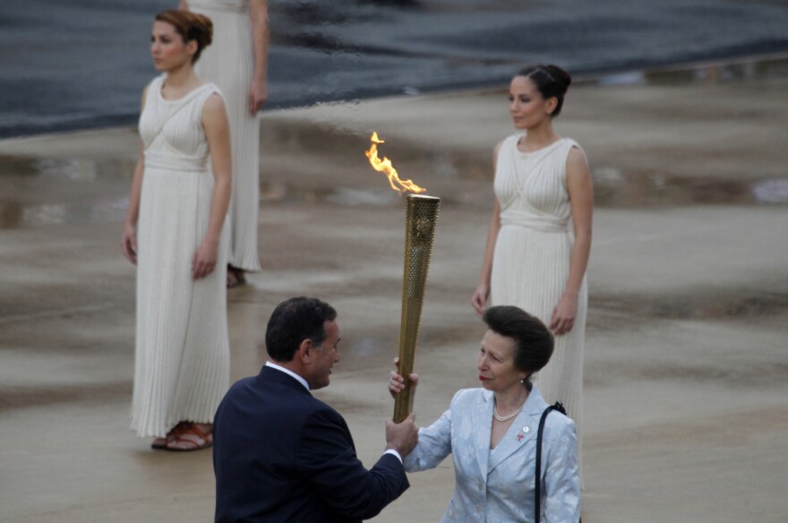 President of the Greek Olympic Committee Spyros Kapralos passes the torch to Britain's Princess Anne, right.