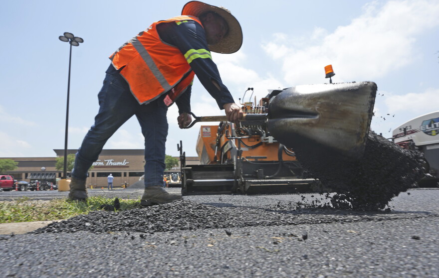 A man shovels hot asphalt during a parking lot
