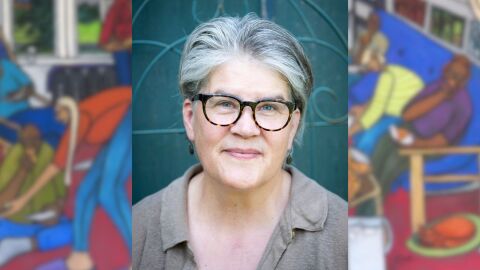 A person in front of a teal background wearing glasses and a blurred painting behind them