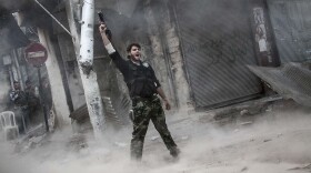A rebel fighter raises his weapon after firing a missile Sunday toward Syrian government troops in the northern city of Aleppo. Syria's largest city has been the scene of heavy fighting for the past three months. Both sides control part of the city, and the fight has been a stalemate recently.