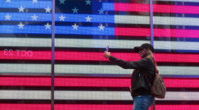 A person in a mask takes a selfie in front of the American flag on October 22, 2020, in New York City. (Gary Hershorn/Getty Images)