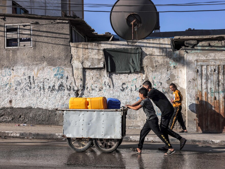 Youths push a cart loaded with jerrycans to be filled with in the southern Gaza Strip on October 31, 2023. A lack of drinking water is leading to a rise in water-borne diseases, according to health officials.