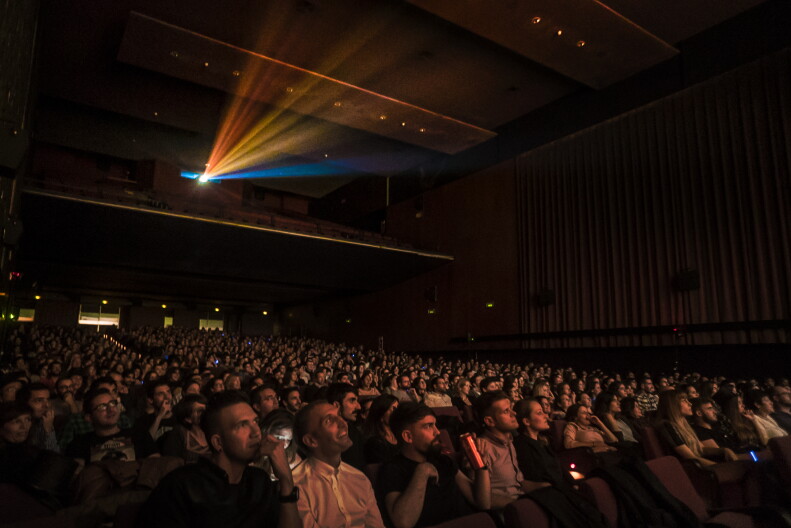 People sit in a theater watching a movie.