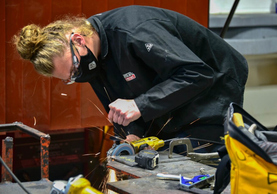 A career and technical education high school student in Elkhart grinds a piece of metal before welding it.