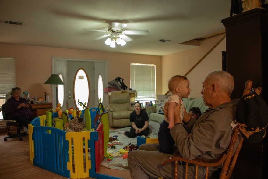 Joe Ponce Jr., right, holds his great-grandson at his home in Fort Worth. He and his wife Arlene, far left, took in their granddaughter and her kids to help them save money during the COVID-19 pandemic.