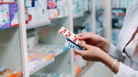 Pharmacist holding medicine box and capsule packs.