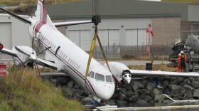 A crane hoists a PenAir Saab 2000 airplane on Oct. 18, 2019. One person was killed and multiple people were injured when the plane went off the runway while attempting to land the evening before. (Photo by Laura Kraegel/KUCB)