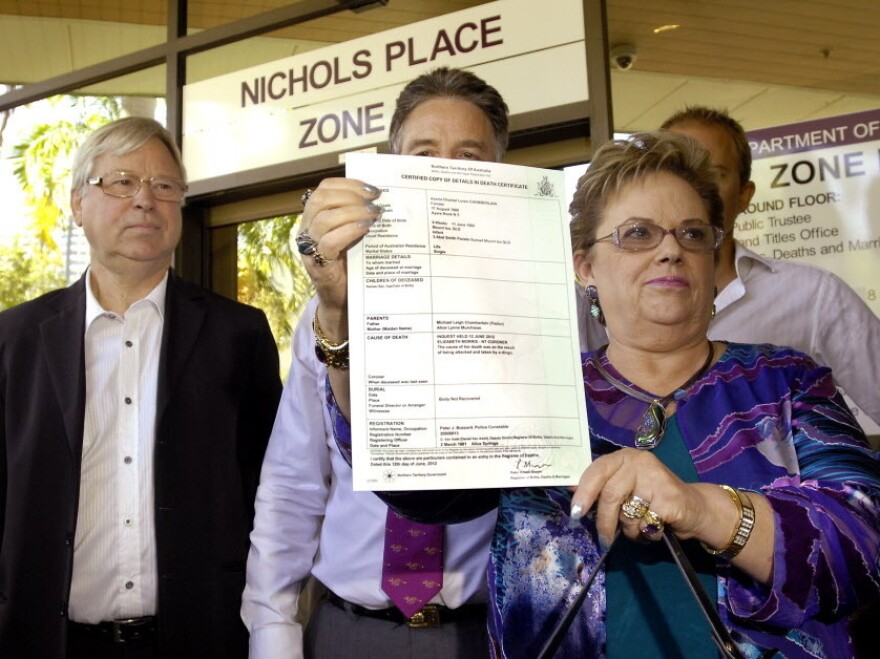 Lindy Chamberlain-Creighton holds her daughter Azaria's death certificate as ex-husband Michael Chamberlain (left) looks on after a coroner ruled today that a dingo snatched the baby from a tent in the Australian desert 32 years ago.