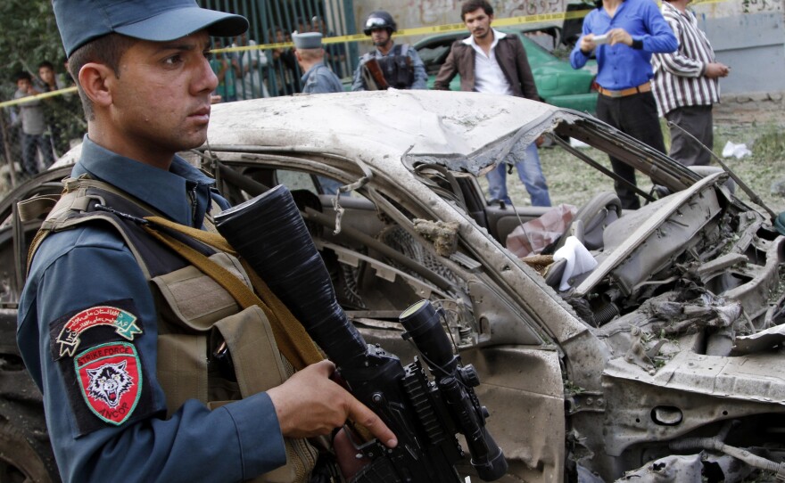 An Afghan policeman stands guard at the scene of a suicide car bomber attack that struck outside the Afghan Supreme Court in Kabul, on June 11.