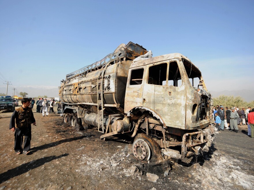 Afghan policemen and locals watch a burned-out fuel truck, supplying a U.S.-run base, after being targeted by a bomb near Bagram Air Field near Kabul on Oct. 26. Attacks on convoys carrying supplies to U.S. troops are costly — both in monetary terms and in human life.