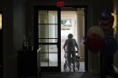 A woman uses a walker as she exits a dark room 