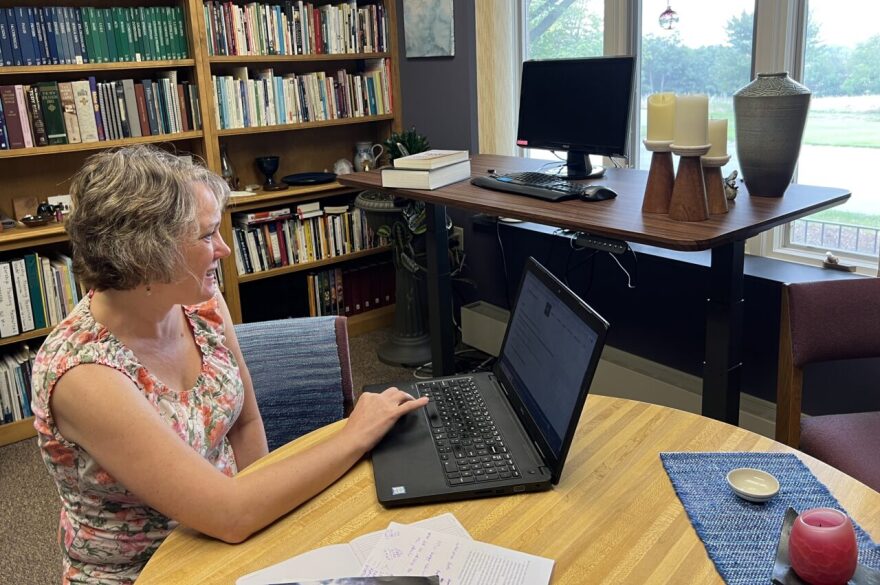 Pastor Rachel Nolt reviews solar savings on her laptop at a table in her office.