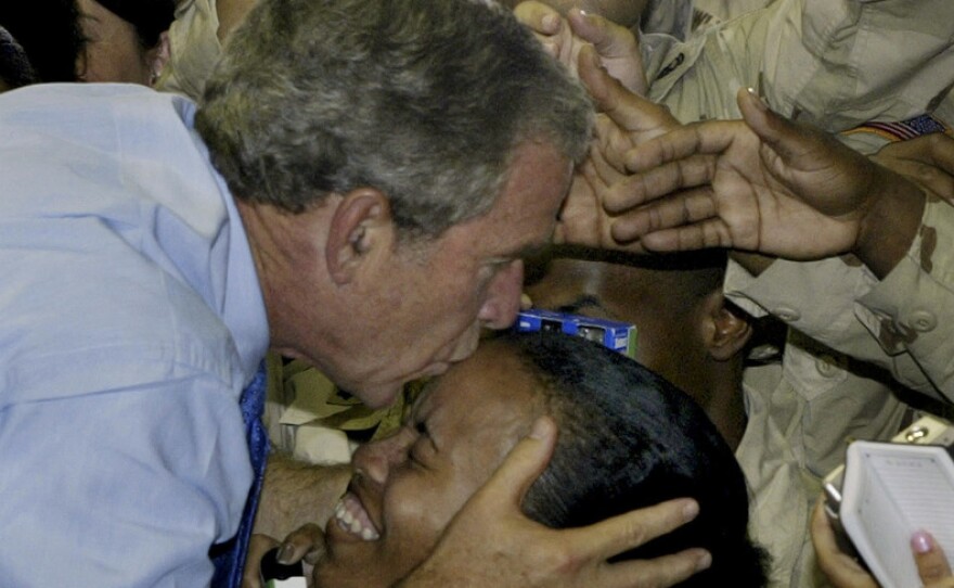 President George W. Bush kisses a soldier as he greets U.S. military personnel at As-Sayliyah base near Doha, Qatar, 2003.