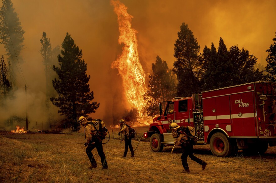 Firefighters work to keep the Oak Fire from reaching a home in the Jerseydale community of Mariposa County, Calif., on Saturday.