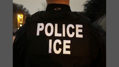 Back of a man wearing uniform that says "POLICE ICE" on it