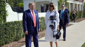 Donald Trump and Melania Trump standing on a sidewalk outside a building