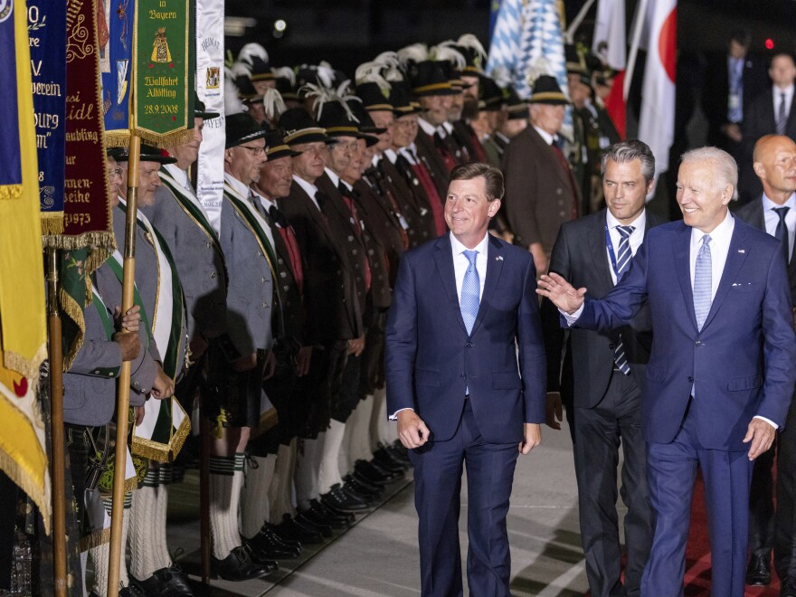 President Biden waves as he walks past Bavarian mountain riflemen and traditional costumers after his arrival in Germany on Saturday ahead of the G7 summit.