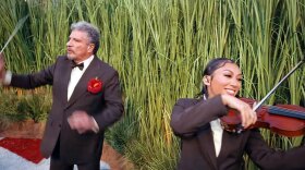 In this image from NFL video, Giancarlo Guerrero, Sarasota Orchestra music director, waves his baton as he "conducts" dozens of violinists during Bad Bunny's halftime show during the Super Bowl on Sunday, Feb. 8, 2026.
