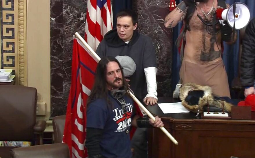 In this image from video, Paul Allard Hodgkins, 38, of Tampa, front, stands in the well on the floor of the U.S. Senate on Jan. 6, 2021, at the Capitol in Washington.
