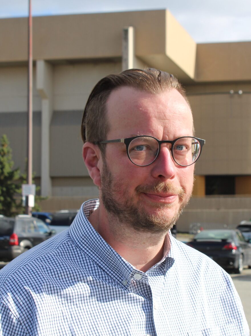A white mane with glasses and a beard with his haiir gelled back